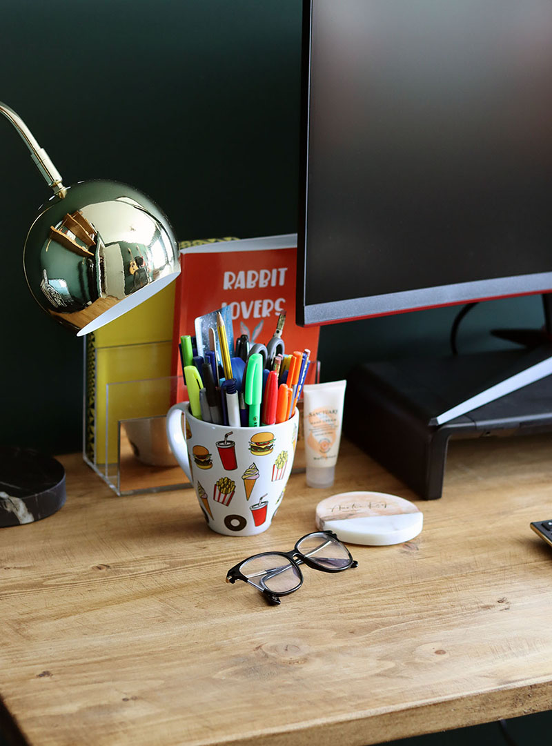 desk setup with a gold desk lamp, pen pot and reading glasses displayed on top