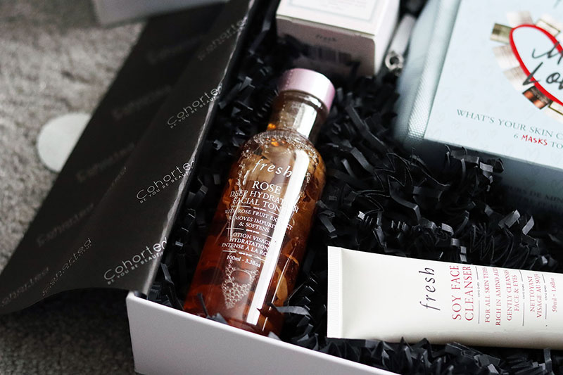 a bottle of facial toner laid on black crinkled packing paper in a luxury box