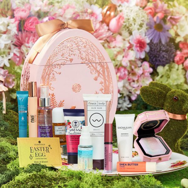 a Glossybox branded pink box in the shape of an Easter egg with lots of beauty products displayed in front of it
