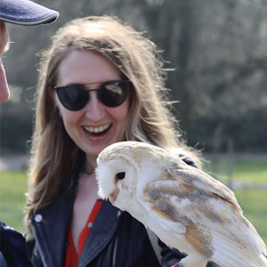 a woman smiling whilst holding a barn owl